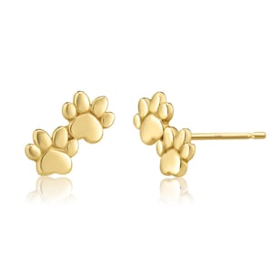 May include: A pair of gold-colored stud earrings, each featuring a paw print design. The earrings are presented on a white background, showcasing their polished finish and intricate details. The paw print design is a popular theme for pet lovers.