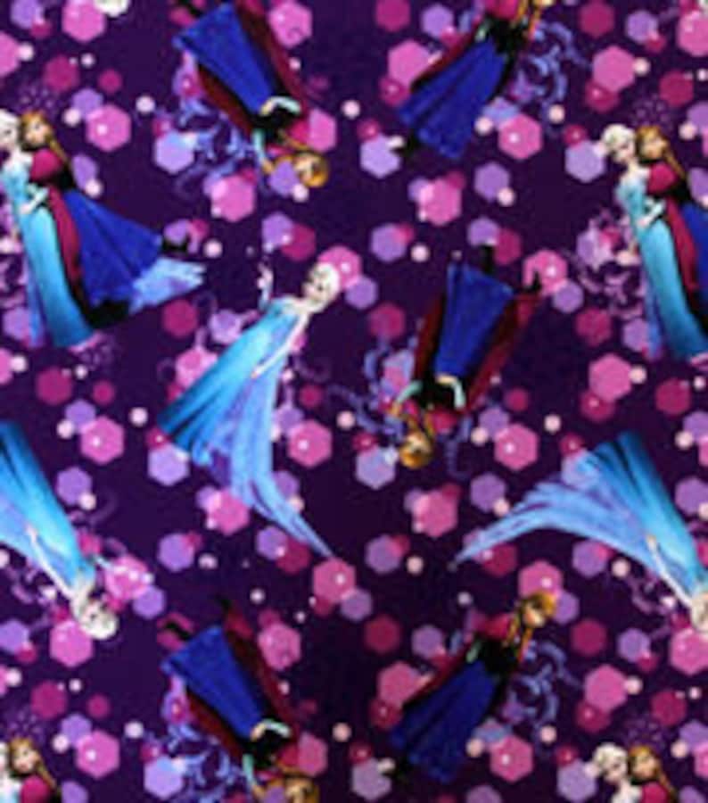 Puede incluir: Una tela con un patr&oacute;n repetido que presenta a los personajes Anna y Elsa de la pel&iacute;cula Frozen. Los personajes est&aacute;n sobre un fondo morado oscuro con formas geom&eacute;tricas rosas y moradas.