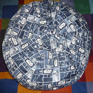 May include: A blue and white bean bag chair with a Star Wars pattern. The pattern features various characters and the words "Star Wars" repeated throughout.