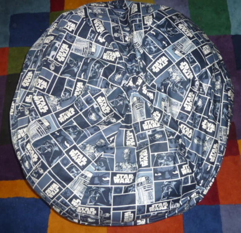 May include: A blue and white bean bag chair with a Star Wars pattern. The pattern features various characters and the words "Star Wars" repeated throughout.