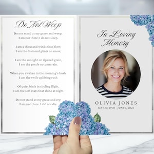 May include: A memorial card with the text "Do Not Weep" and "In Loving Memory." The card features a photo of a woman, Olivia Jones, with dates May 10, 1970 - June 1, 2025. Blue hydrangea flowers decorate the corners.
