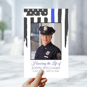 May include: A memorial card featuring a photograph of a police officer in uniform. The card includes an American flag design with a blue stripe, the text "Honoring the Life of JOHN WILLIAMS," and dates.