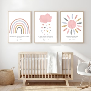 May include: Three framed art prints with pastel illustrations of a rainbow, a pink cloud with hearts, and a sun. Each print has text in Spanish. The prints are displayed above a wooden cot in a nursery setting.
