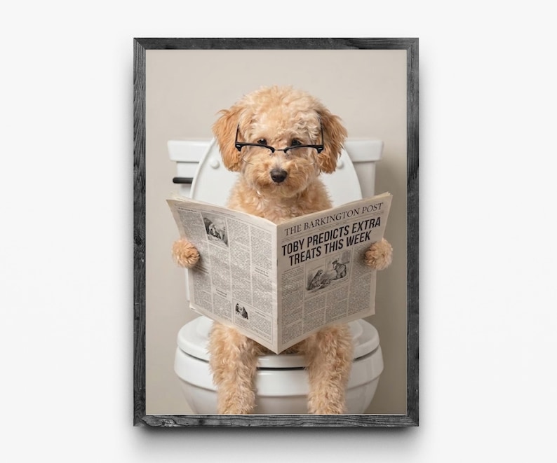 May include: A framed print features a light brown poodle wearing glasses and sitting on a toilet, reading a newspaper. The newspaper headline reads, "TOBY PREDICTS EXTRA TREATS THIS WEEK." The frame is dark gray.