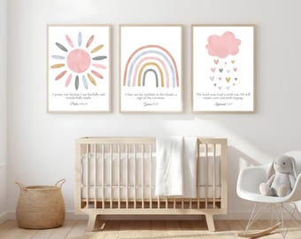 May include: Three framed art prints with pastel illustrations of a sun, rainbow, and cloud with hearts. Each print has a Bible verse. The prints are displayed above a wooden crib in a nursery setting.