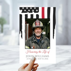 May include: A memorial card with a photograph of a firefighter in uniform, set against a stylized American flag design with a red stripe. The text reads "Honoring the Life of JOHN WILLIAMS" with dates. The card is held by a hand.