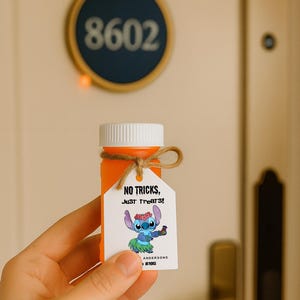 Puede incluir: Una botella naranja con tapa blanca y una pequeña etiqueta atada con hilo. La etiqueta presenta un personaje de dibujos animados y el texto "NO TRICKS, JUST TREATS". La botella se sostiene frente a una puerta blanca con manija dorada.