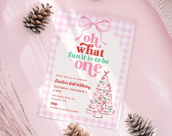 May include: A pink and white gingham-patterned invitation with the text "oh what fun it is to be one." The invitation includes details for Emilia's first birthday, with a Christmas tree illustration and decorative bows. Pinecones and a pink background complete the festive design.