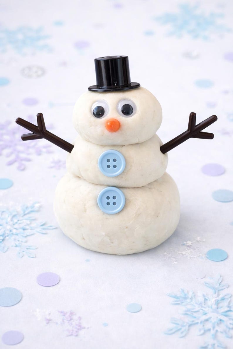 May include: A snowman made of dough, featuring a black top hat, googly eyes, and an orange nose. It has brown twig arms and light blue buttons. The snowman is a festive decoration.