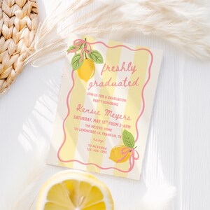 May include: A graduation party invitation with a lemon theme. The invitation has a yellow and white striped background with a pink border. The text "freshly graduated" is written in pink script, along with party details.