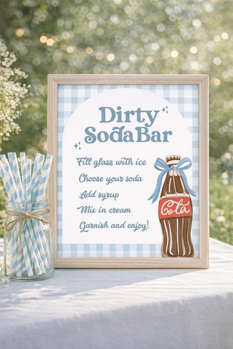 May include: A framed sign with a light blue gingham background and the words "Dirty Soda Bar." It includes instructions for making a soda, and a cartoon illustration of a cola bottle with a blue bow. A jar of blue and white striped straws sits to the left.