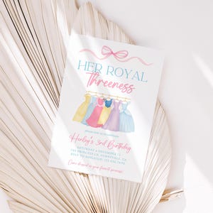 Peut inclure: Une invitation blanche avec le texte "HER ROYAL Threeness" et "Henley's 3rd Birthday" en rose et turquoise. La carte présente des illustrations à l'aquarelle de robes de princesse de différentes couleurs, avec un nœud rose en haut.