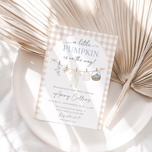 May include: Baby shower invitation with a gingham background and the text "a little PUMPKIN is on the way!". The invitation includes details for Avery Collins' baby shower, with a clothesline graphic featuring baby clothes and a basket.