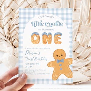 Pode incluir: Cartão de convite com padrão xadrez azul e branco com o texto "Our Sweet Little Cookie is Turning One". Apresenta uma ilustração de homem de gengibre e detalhes do evento.