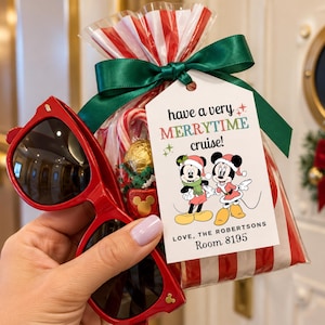 May include: A pair of red sunglasses held next to a clear plastic gift bag with red and white stripes, tied with a green ribbon. A white tag attached reads: have a very MERRYTIME cruise! LOVE, THE ROBERTSONS Room 8195, featuring Mickey and Minnie Mouse.