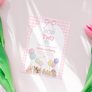 Könnte beinhalten: Eine Geburtstagseinladung mit rosa und weißem Vichy-Muster. Der Text lautet "HOP TWO IT!". Die Einladung zeigt Illustrationen von Hasen, die Luftballons halten. Der Text lautet "Amelia's 2nd birthday".