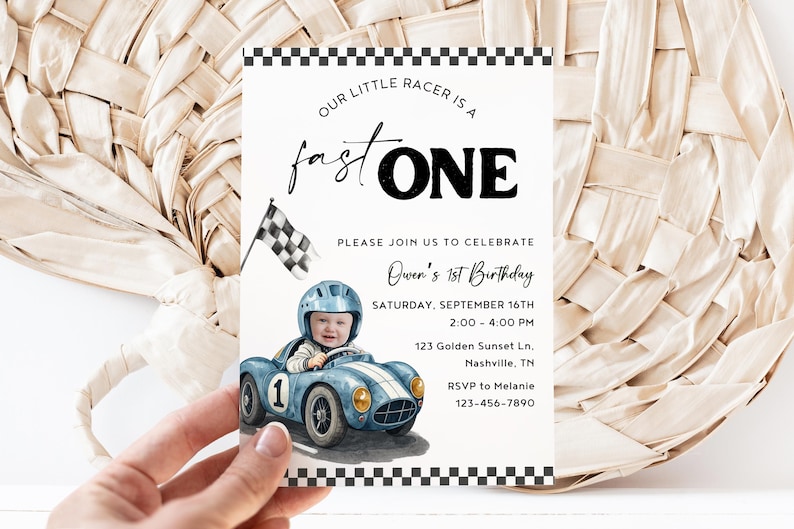 May include: A rectangular birthday invitation card featuring a black and white checkered border. The text reads: Our little racer is a fast ONE, Please join us to celebrate Owen's 1st Birthday, Saturday, September 16th, 2:00-4:00 PM, 123 Golden Sunset Ln, Nashville, TN, RSVP to Melanie 123-456-7890. It includes a watercolor illustration of a child in a blue race car with a checkered flag.