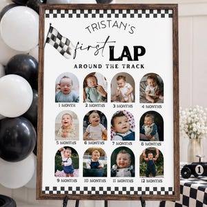 May include: A framed sign with the text "Tristan's first LAP around the track" and photos of a baby from 1 to 12 months. The sign has a checkered flag and border, with black and white balloons in the background.