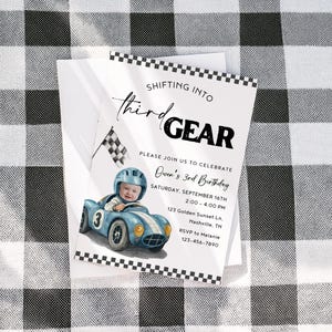 May include: A birthday invitation with a racing theme. The invitation features a watercolour illustration of a child in a blue race car. Text includes "Shifting into Third Gear" and party details.