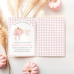 May include: A pink and white gingham patterned invitation with the text "Our Little Pumpkin is One" and "Madeline's 1st Birthday". The invitation features a pumpkin graphic with a bow. Pink pumpkins and pampas grass are in the background.