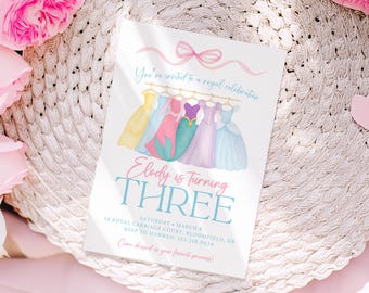 May include: A white invitation card with a watercolor illustration of princess dresses. The text reads "Elody is Turning THREE" and invites guests to a royal celebration. Additional details include the date, location, and RSVP information.