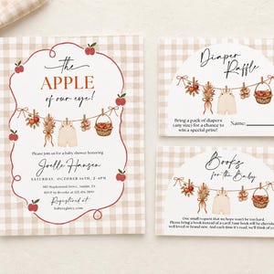 May include: A set of three rectangular baby shower cards with a beige and white gingham pattern. The cards feature watercolor illustrations of apples, dried flowers, and baby clothes on a clothesline with the text "the APPLE of our eye!"