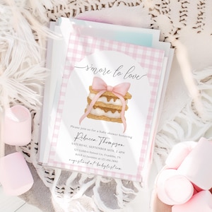 May include: Baby shower invitations featuring a pink gingham design and a s'more illustration. The text reads "smore to love" and includes event details for Rebecca Thompson's baby shower, including date, time, and location.