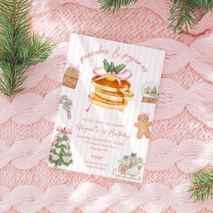 以下が含まれることがあります： 「pancakes & pajamas」と「Abigail's 1st Birthday」の文字が入った誕生日招待状。パンケーキ、ジンジャーブレッドハウス、キャンディケーン、スノーグローブ、ジンジャーブレッドマン、クリスマスツリー、そりのイラストが特徴です。
