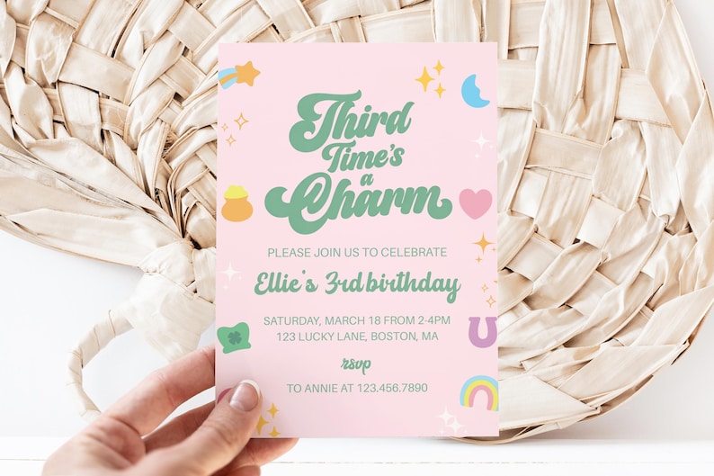 May include: A pink invitation card with the text "Third Time's a Charm" in green script, celebrating Ellie's 3rd birthday. The card includes details like the date, time, and location, along with a rainbow, heart, and other decorative elements.