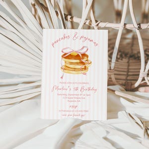 May include: A pink and white striped invitation card with the text "pancakes & pajamas" and "Marlow's 5th Birthday". The card features a watercolor illustration of pancakes with a pink ribbon and butter.