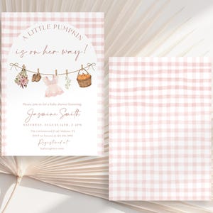 Peut inclure: Une invitation &agrave; une baby shower avec un fond &agrave; carreaux roses. L'invitation indique "A Little Pumpkin is on her way !" avec des illustrations de v&ecirc;tements de b&eacute;b&eacute; et un panier de citrouilles. Elle comprend le nom Jasmine Smith et les d&eacute;tails de l'&eacute;v&eacute;nement.