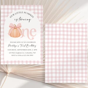 Op de afbeelding: Een rechthoekige verjaardagsuitnodigingskaart met een lichtroze en wit gingham-patroon. De kaart toont een pompoenillustratie met een bijpassende gingham-strik, de tekst Our Little Pumpkin is turning one en evenementdetails.