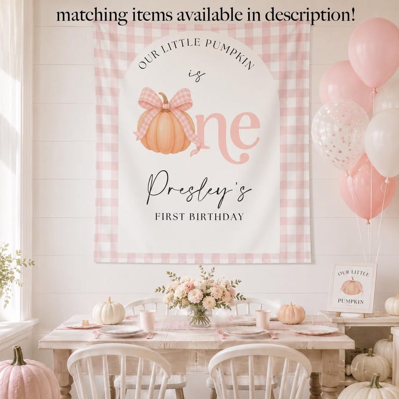 Op de afbeelding: Een rechthoekige stoffen achtergrond met een roze en witte gingham rand, een centrale boog en een perzikkleurige pompoen met een roze geruite strik. De tekst luidt: Our Little Pumpkin is one, Presley's First Birthday. Bijpassende items beschikbaar.