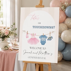 Puede incluir: Un letrero rectangular de revelación de género sobre un caballete de madera con el texto Tutus OR TOUCHDOWNS? e ilustraciones de zapatillas de ballet rosas, un tutú rosa, un body azul con el número 00 y tacos azules en un tendedero.