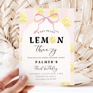 May include: A pink and white invitation with the text "Easy Peasy Lemon Three-zy" and lemon illustrations. The invitation is for a third birthday party and includes the date, time, and location.