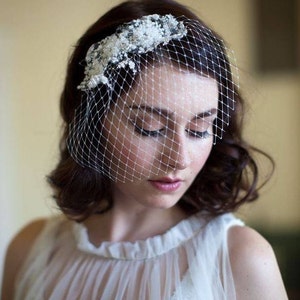 Puede incluir: Una novia con un velo blanco con un dise&ntilde;o floral y un vestido blanco.