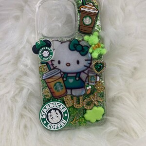 May include: Clear phone case decorated with green glitter, a Hello Kitty figure, Starbucks logos, and a coffee cup. Additional embellishments include a green bow, a green teddy bear, and gold lettering that spells "BUCKS".