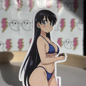 May include: A die-cut sticker featuring an anime-style illustration of a person in a blue bikini holding a small object. The sticker has a white border and the artist's signature is visible. The background has repeating patterns of pink lightning bolts and white ghosts.