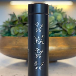May include: Black stainless steel water bottle with a repeating pattern of white silhouettes of a Pokemon character, Eevee.