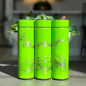 May include: Three vibrant green insulated water bottles, each with a silver dragon design. The bottles are cylindrical with black rims and bases. The dragon design wraps around the bottle. The bottles are displayed on a grey surface.
