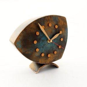 Brown wooden standing  clock with gold turquoise accents, The clock face features gold dots on round and two gold hands for hours and minutes  face, clock is placed on a stable surface and a white background