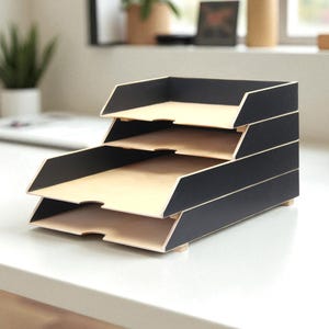 Può includere: Un organizer da scrivania a tre livelli dal design moderno. L'organizer presenta un esterno nero con vassoi interni color legno naturale. I vassoi sono impilati, creando un aspetto a gradini. L'organizer è progettato per contenere carte e documenti.