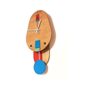 May include: A wooden wall clock with a light brown oval face and a pendulum. The clock features a red rectangle, blue and green squares, and a blue circle. The clock hands are white.
