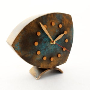 Brown wooden standing  clock with gold turquoise accents, The clock face features gold dots on round and two gold hands for hours and minutes  face, clock is placed on a stable surface and a white background