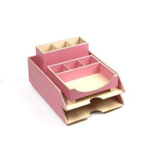 Op de afbeelding: Een roze houten bureau-organizer met meerdere compartimenten en trays. De organizer heeft een gelaagd ontwerp, met een pennenhouder, een tray met verdelers en een papiertray. De binnenkant van de compartimenten is van natuurlijk hout.