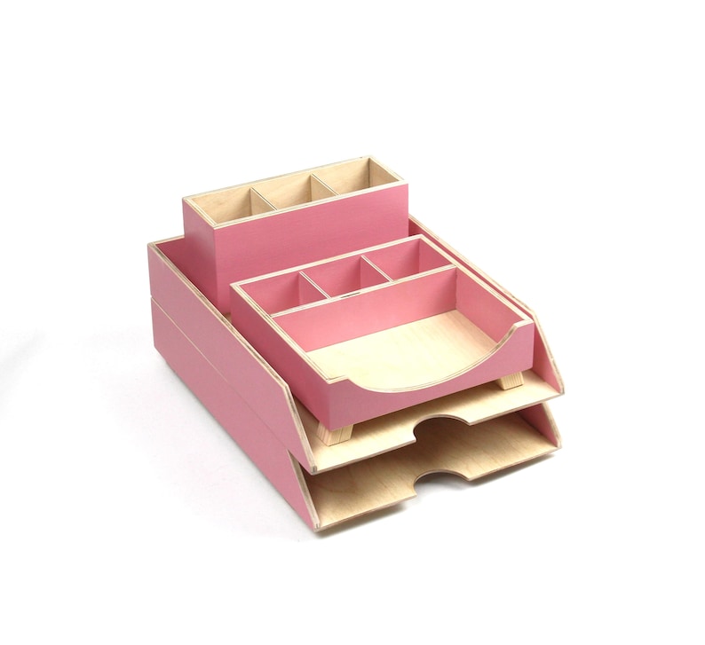 Op de afbeelding: Een roze houten bureau-organizer met meerdere compartimenten en trays. De organizer heeft een gelaagd ontwerp, met een pennenhouder, een tray met verdelers en een papiertray. De binnenkant van de compartimenten is van natuurlijk hout.