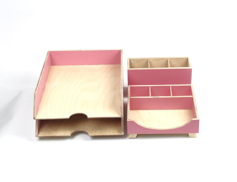 Op de afbeelding: Een tweedelige bureau-organizer set. De set bevat een papierbak met twee niveaus en een bureau-organizer met meerdere compartimenten. Beide stukken zijn gemaakt van lichtgekleurd hout met roze accenten op de randen en verdelers.