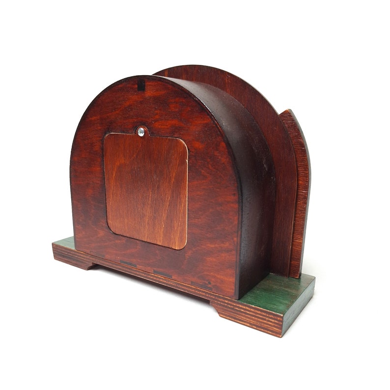 May include: A wooden desk tidy with a dark brown finish. The organiser has a curved top and a rectangular opening on the back. The base is painted green. The wood grain is visible.