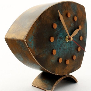 Brown wooden standing  clock with gold turquoise accents, The clock face features gold dots on round and two gold hands for hours and minutes  face, clock is placed on a stable surface and a white background