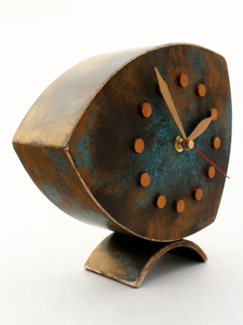 Brown wooden standing  clock with gold turquoise accents, The clock face features gold dots on round and two gold hands for hours and minutes  face, clock is placed on a stable surface and a white background